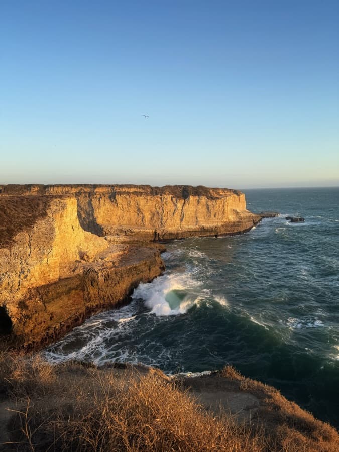 Golden sea cliffs and crashing waves at sunset